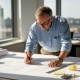Engineer checking blueprints in sunlit office