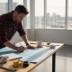 Engineer reviewing blueprints at drafting table in sunny office