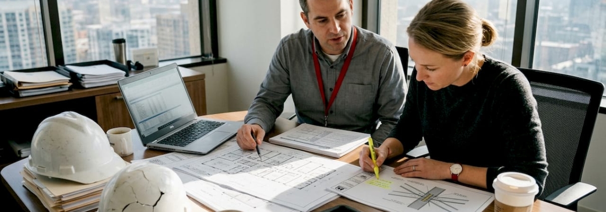 Forensic engineers discussing project documents in office